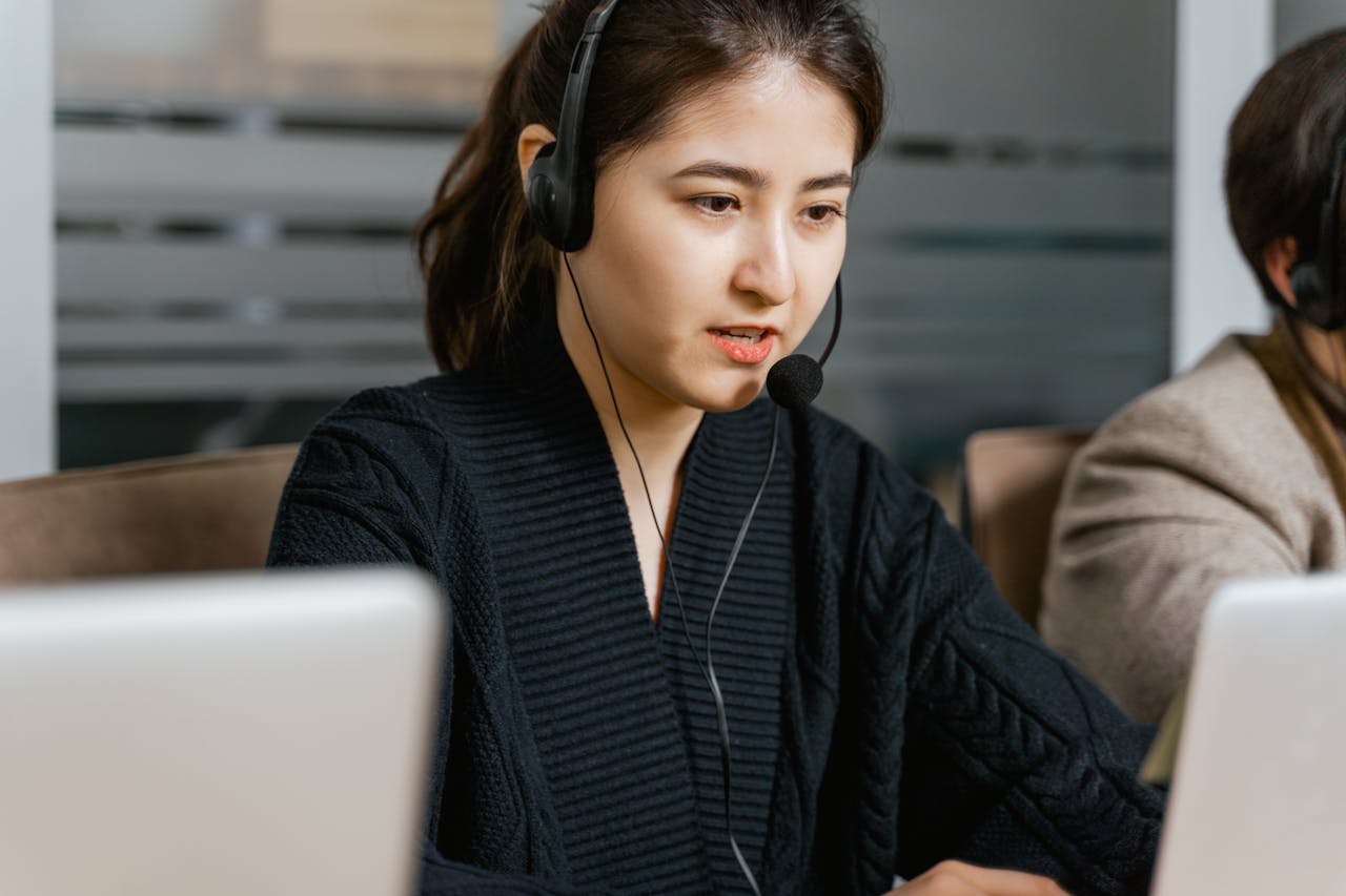 about-bg Asian woman in a call center focused on customer support tasks using a laptop.